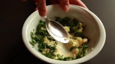 Küçük beyaz kasede tereyağı, sarımsak ve maydanozu karıştırarak sarımsak hazırlayan kadın eli.