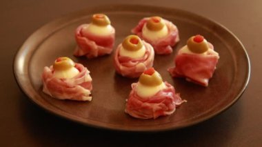 Kadınların elleri Cadılar Bayramı 'nda Prosciutto, Mozzarella ve Yeşil Zeytinli Korku Elleri Yemeği hazırlıyor.