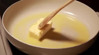  Bir tavada eriyen tereyağı çubuğu yavaş yavaş pürüzsüz, altın bir sıvıya dönüşüyor.