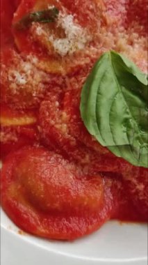 Taze pişmiş ravioli, domates soslu bir tabakta servis edilir.