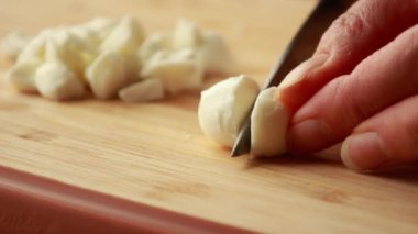 Taze mozzarella toplarını tahta kesme tahtasının üzerinde küçük küplere ayırmak.