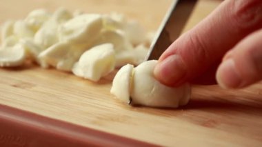 Taze mozzarella toplarını tahta kesme tahtasının üzerinde küçük küplere ayırmak.