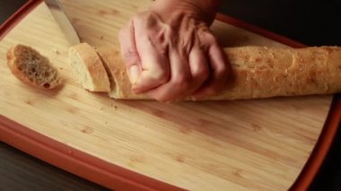 Tahta tahtaya yakın plan Crostini yapmak için Fransız ekmeğini dilimlemek.