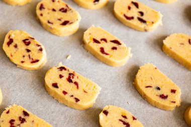 unbaked Christmas cookies with dried cranberries and orange zest arranged on a baking tray, ready to bake clipart