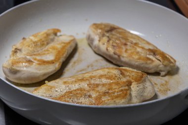 Cooking Chicken Fillet Breast in a White Pan  Close-Up clipart