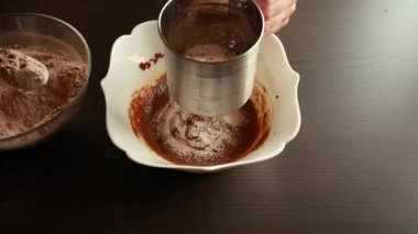 Karıştırılmış un ve kakao tozunu çikolatalı kurabiye yapmak için ıslak malzemelere yakın çekim