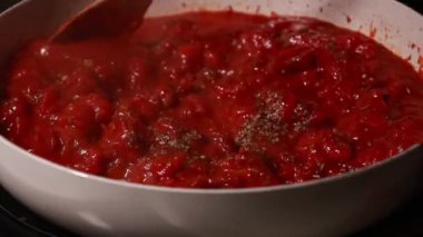 Koyu beyaz bir tencerede pişirilmiş domates sosunun yakın çekimi
