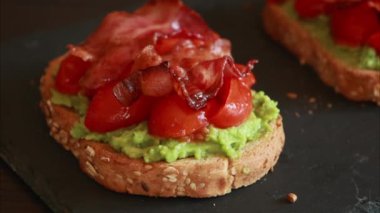 Domatesli avokado tostu ve yakın plan kızarmış domuz pastırması.
