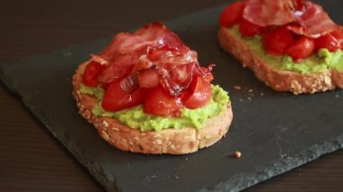 Domatesli avokado tostu ve yakın plan kızarmış domuz pastırması.