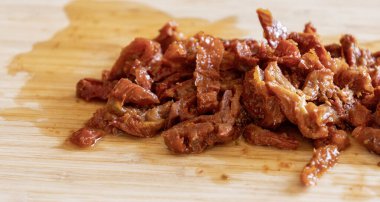 Tahta üzerinde doğranmış güneşte kurutulmuş domatesler. Yakın plan.