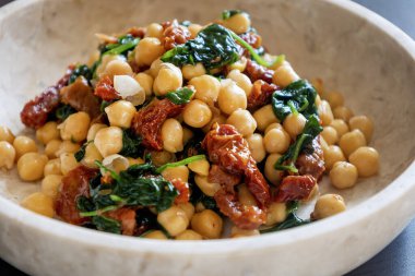 Nohutlu sağlıklı salata, güneşte kurutulmuş domates ve ıspanak yakın çekimi.