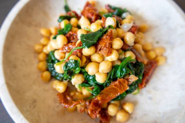 Nohutlu sağlıklı salata, güneşte kurutulmuş domates ve ıspanak yakın çekimi.