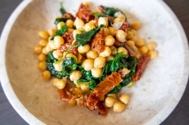 Nohutlu sağlıklı salata, güneşte kurutulmuş domates ve ıspanak yakın çekimi.