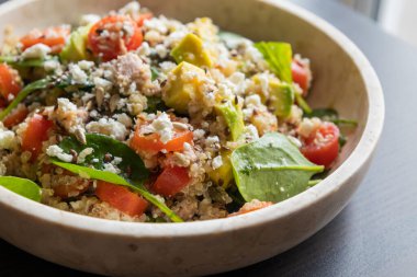 Quinoa, avokado, karışık tohum ve peynirden yapılmış canlı ve besleyici bir salatanın yakın çekimi, sağlıklı bir yemek için protein ve sağlıklı yağlarla paketlenmiş.