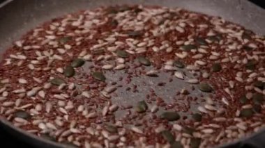 Bir tavada pişirilen ayçiçeği, balkabağı ve keten tohumlarının karışımının yakın çekim videosu sağlıklı ve besleyici bir bileşen hazırlıyor.