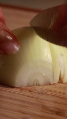 Bir kadının ellerinin taze soğanı bıçakla doğrarken yakın plan fotoğrafı.