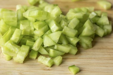  Tahta kesme tahtasının üzerinde taze salatalık doğra.