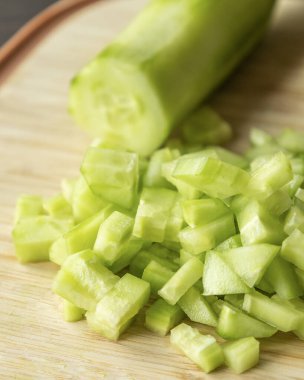  Tahta kesme tahtasının üzerinde taze salatalık doğra.