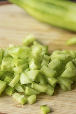  Tahta kesme tahtasının üzerinde taze salatalık doğra.