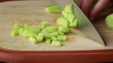 Kadın elleri ahşap kesim tahtasının üzerinde salatalık doğruyor.