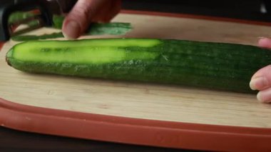  Kadın elleri ahşap kesim tahtasının üzerinde salatalık soyuyordu.