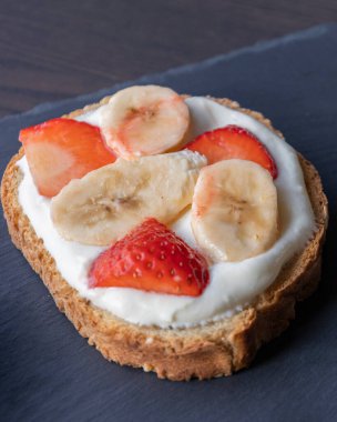  Lezzetli bir tost, kremalı ricotta, taze çilek dilimleri ve muz dilimleri, tatlı ve sağlıklı bir kahvaltı için mükemmel.