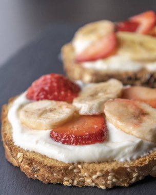  Lezzetli bir tost, kremalı ricotta, taze çilek dilimleri ve muz dilimleri, tatlı ve sağlıklı bir kahvaltı için mükemmel.