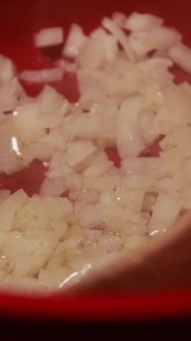  Kırmızı bir tencerede doğranmış soğan pişirmek.