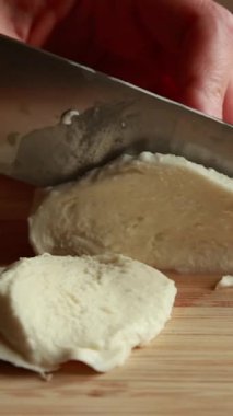 Taze mozzarella peyniri ahşap bir tahtada dilimleniyor.