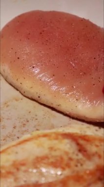 Büyük beyaz bir tavada tavuk göğsü pişiriyorum.