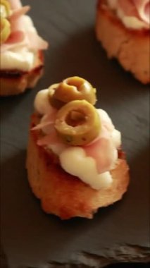 İtalyan aperatif bruschetta, Mortadella salamı, ricotta ve yakın plan yeşil zeytinli crostini.