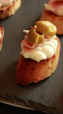 İtalyan aperatif bruschetta, Mortadella salamı, ricotta ve yakın plan yeşil zeytinli crostini.