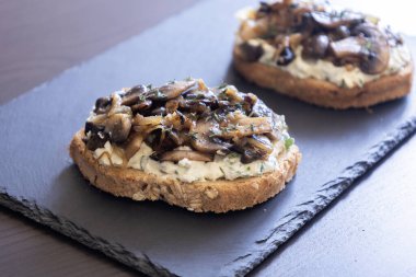 Siyah taşlı tabakta krem peynirli, mantarlı ve karamelli soğanlı nefis mantarlı tost.