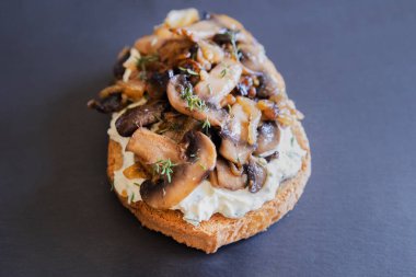 Siyah taşlı tabakta krem peynirli, mantarlı ve karamelli soğanlı nefis mantarlı tost.