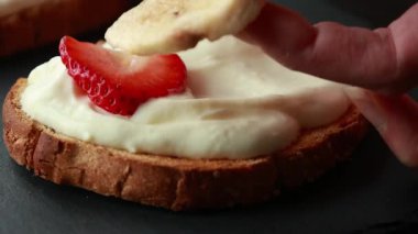 Lezzetli kızarmış ekmek, çırpılmış ricotta, muz ve yakın plan çilek dilimleri.