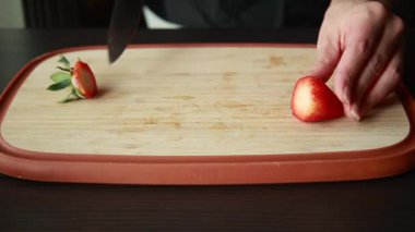 Kadın elleri kesme tahtasında taze çilek dilimliyor.