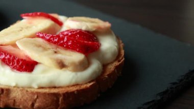 Lezzetli kızarmış ekmek, çırpılmış ricotta, muz ve yakın plan çilek dilimleri.