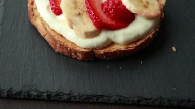 Lezzetli kızarmış ekmek, çırpılmış ricotta, muz ve yakın plan çilek dilimleri.