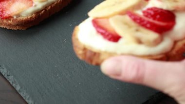 Lezzetli kızarmış ekmek, çırpılmış ricotta, muz ve yakın plan çilek dilimleri.