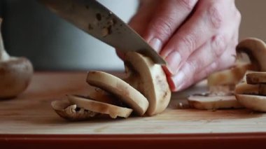 Kadın elleri kesme tahtasının üzerinde mantar kesiyor.