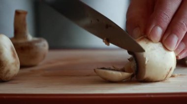 Kadın elleri kesme tahtasının üzerinde mantar kesiyor.