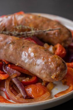  Kırmızı soğan ve kırmızı dolma biberle servis edilen sağlıklı sosisler. Basit ve lezzetli bir yemek. Kolay bir akşam yemeği için mükemmel.