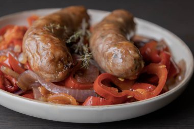  Kırmızı soğan ve kırmızı dolma biberle servis edilen sağlıklı sosisler. Basit ve lezzetli bir yemek. Kolay bir akşam yemeği için mükemmel.