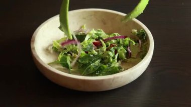 Bir kasede taze ve renkli bir bahar salatasının yakın plan çekimi. İçinde çıtır marul, sulu domates, salatalık ve diğer canlı malzemeler var. Sağlıklı ve ferahlatıcı bir yemek. Her yemek için mükemmel.