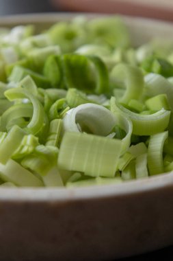 Taze dilimlenmiş pırasa halkaları beyaz bir kasede düzenlenmiş, canlı yeşil halkalarını sergiliyorlar.