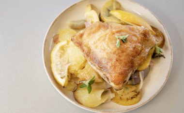  Kavrulmuş tavuk butları limon patatesleri ve arpacık soğanlarıyla dolu bir kasede.
