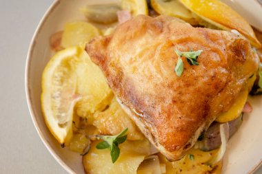  Kavrulmuş tavuk butları limon patatesleri ve arpacık soğanlarıyla dolu bir kasede.