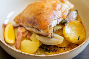 Kızarmış tavuk budu, patates, limon ve soğan ile yakın plan bir tabakta.