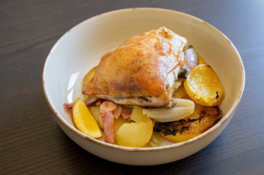 Kızarmış tavuk budu, patates, limon ve soğan ile yakın plan bir tabakta.