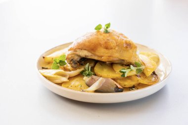 Kızarmış tavuk budu, patates, limon ve soğan ile yakın plan bir tabakta.